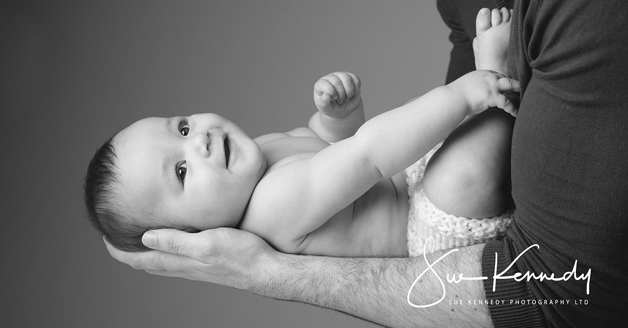 small baby in dads arms in black and white