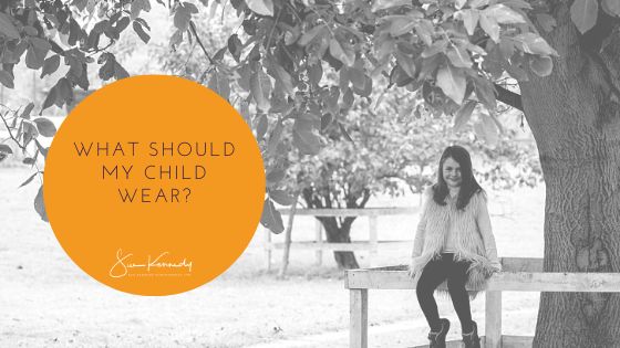blog article header image for what should my child wear with a B&W outdoor photo of a child sat on a fence