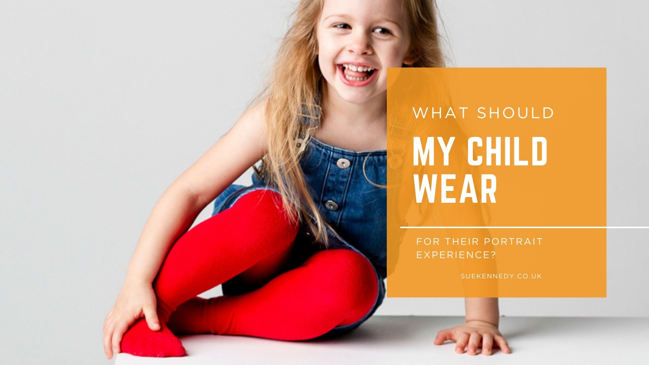 Smiling young child wearing a denim outfit and red tights, laughing confidently during a relaxed portrait experience.