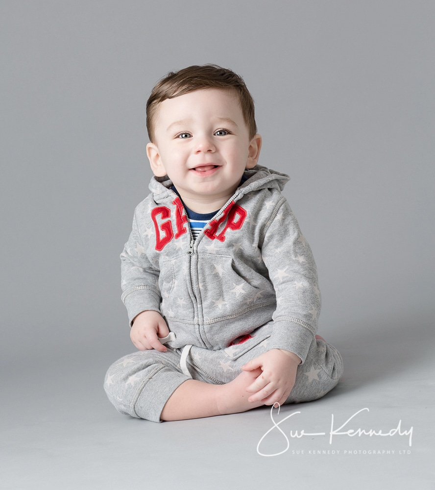 baby boy sitting crossed leg and smiling toward camera