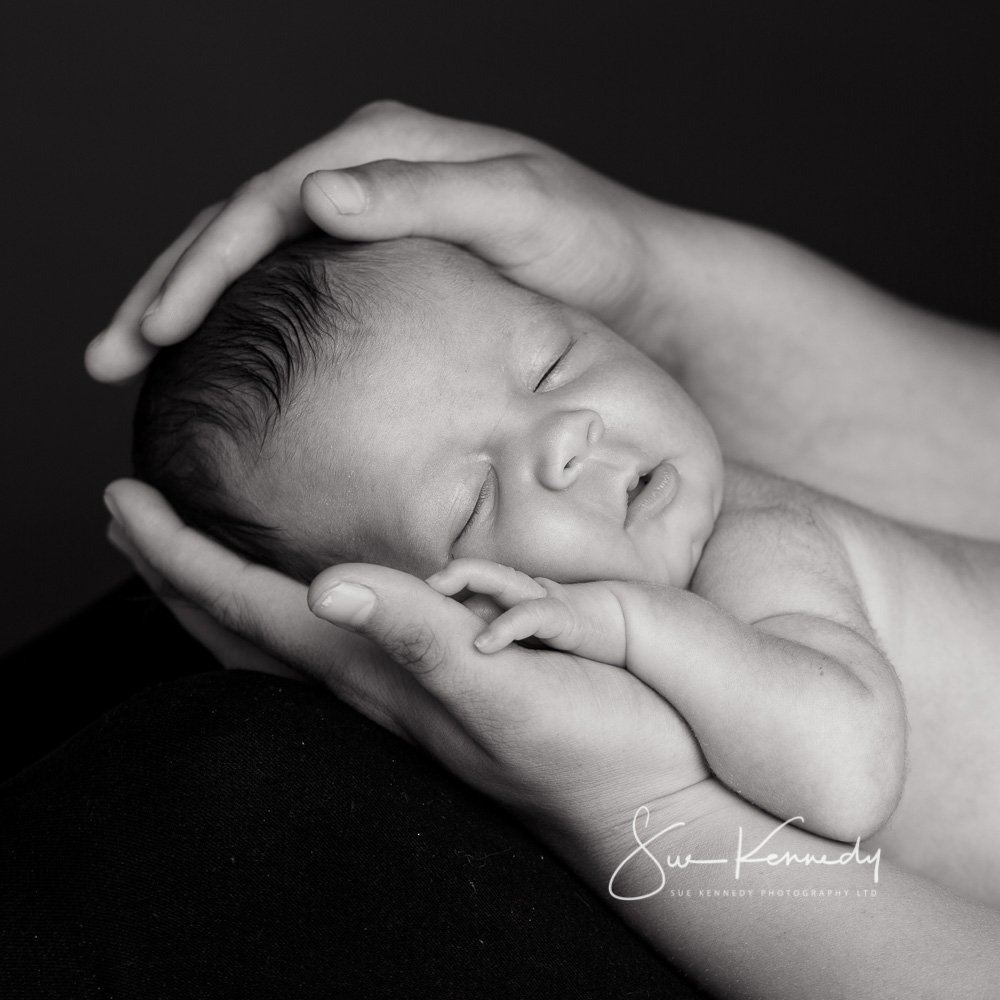 new baby cradled in parents hands & arms asleep