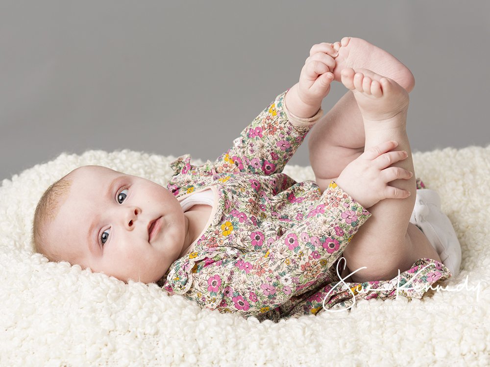 Baby girl lying and grabbing her toes