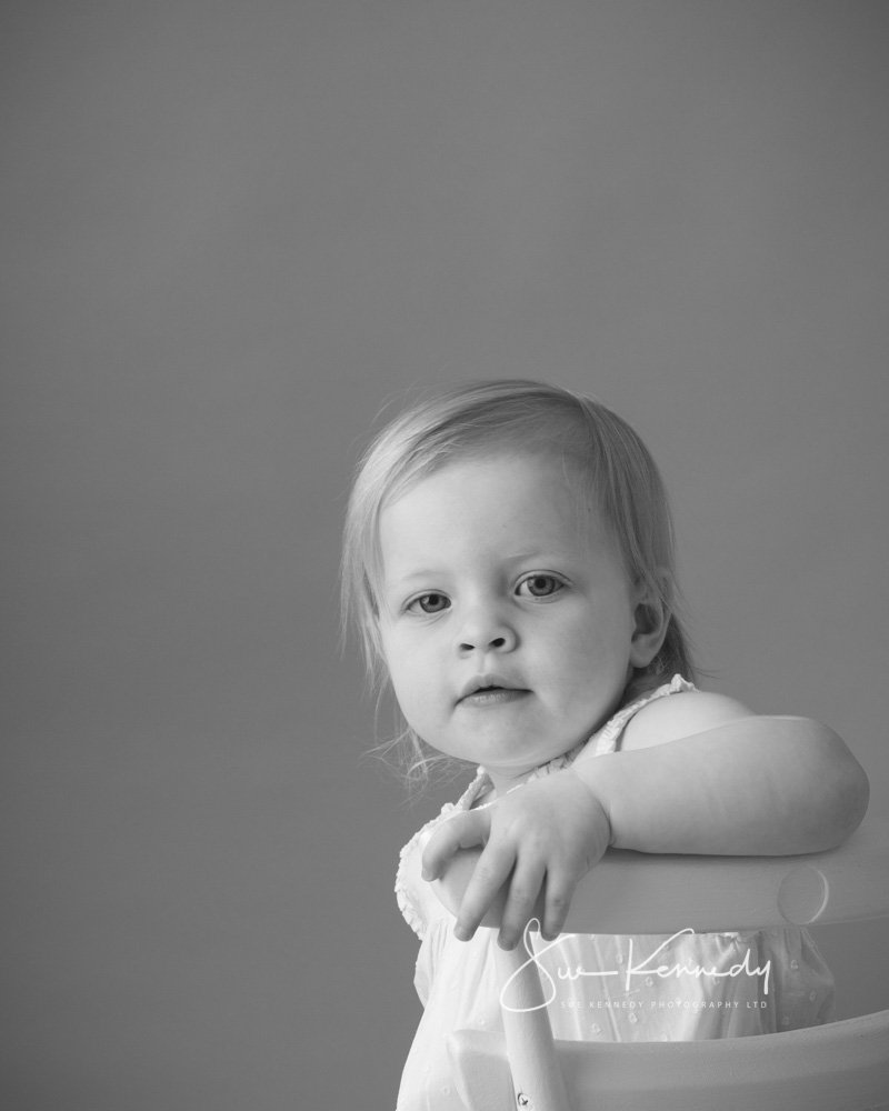 black and white portrait of toddler sat on a chair