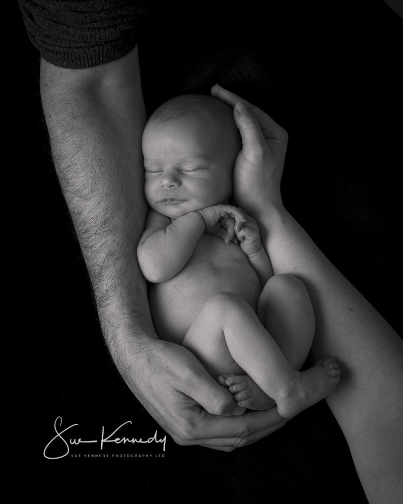 black & white photo of 3 week old baby in parents arms 