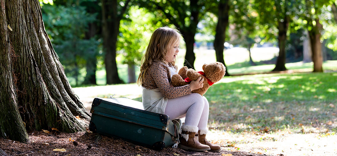 Little girl look at her teddy bear under a tree. Capturing childhood memories with an outdoor child photoshoot image