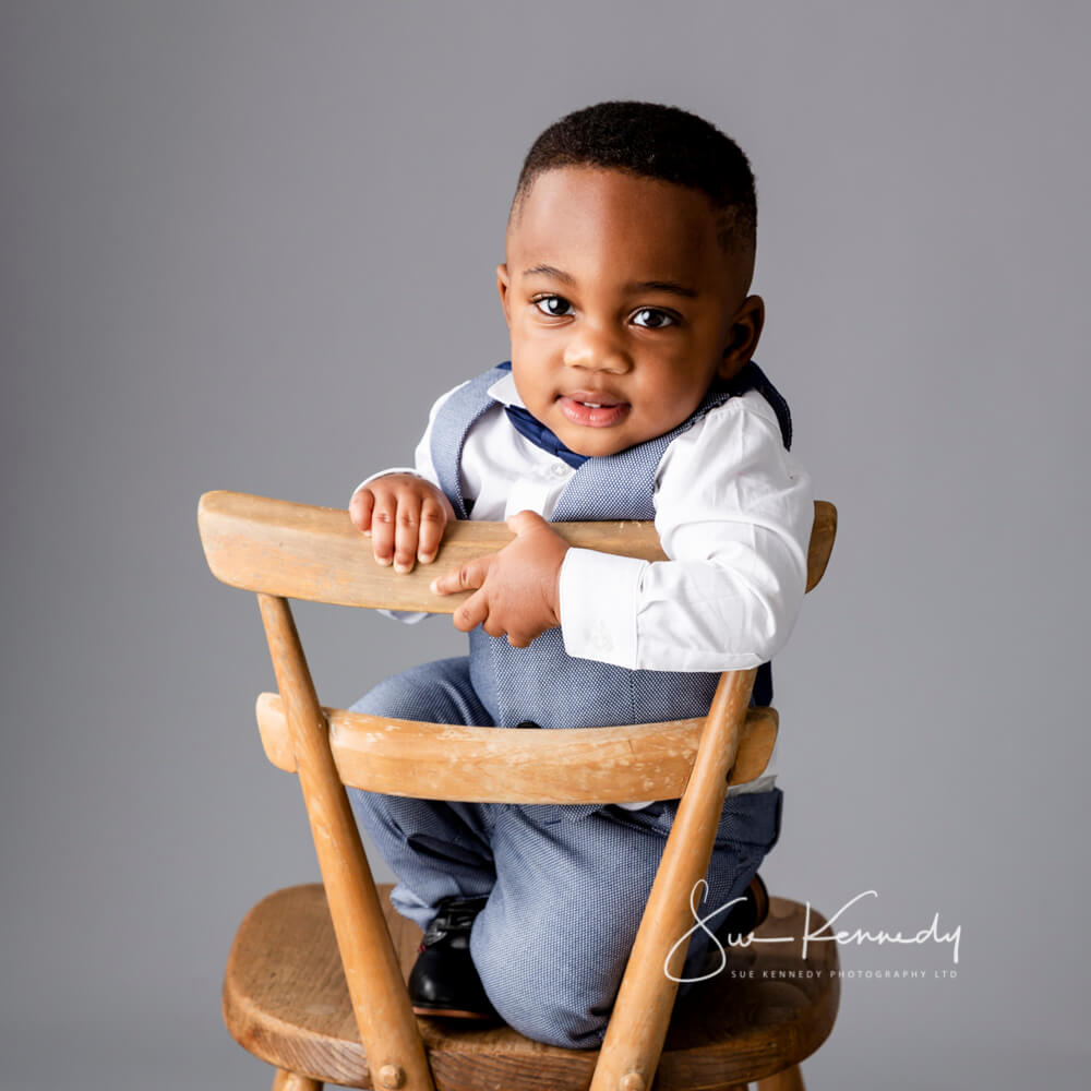 older baby boy sat on a chair during his photoshoot at my photography studio in Harlow. Essex