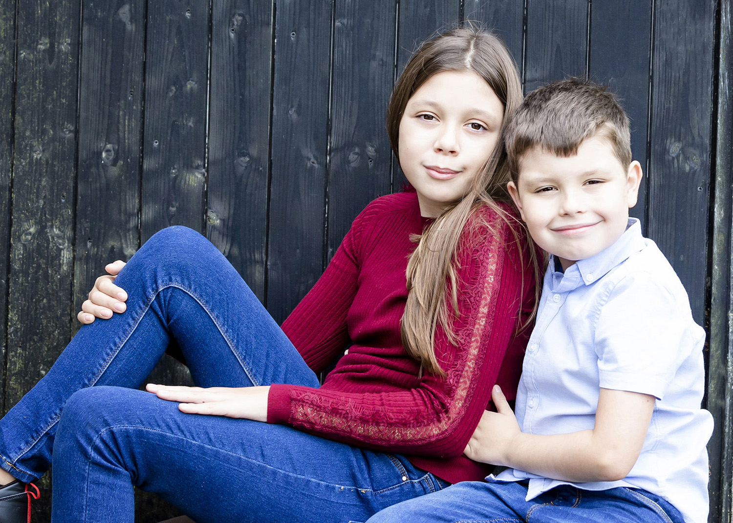 Brother and sister sat together looking toward camera