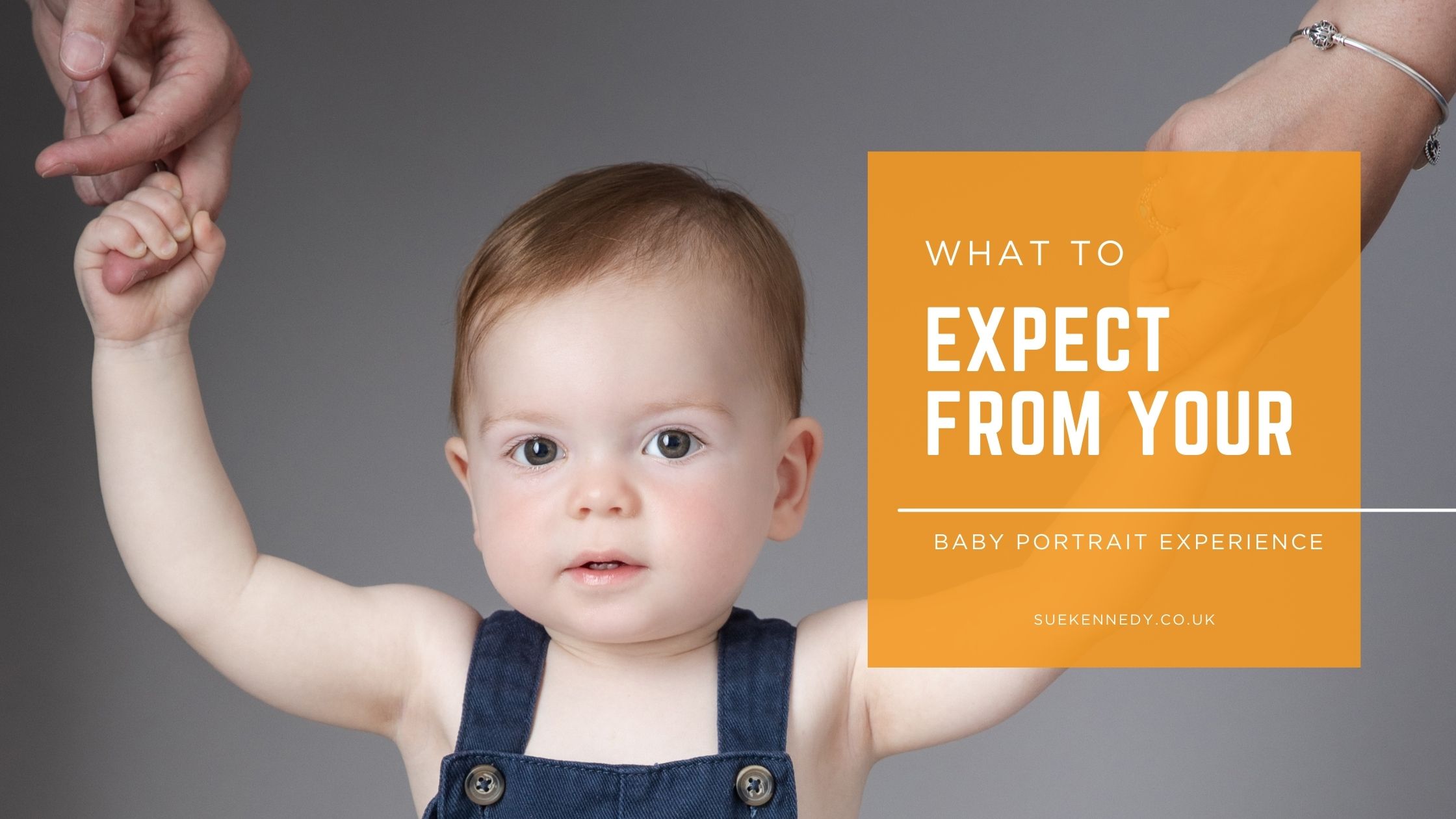 What-to-Expect-From-Your-Baby-Portrait-Experience-Sue-Kennedy-Photography A baby holds onto their parents’ hands while looking toward the camera, used as the header image for “What to Expect From Your Baby Portrait Experience” at Sue Kennedy Photography.