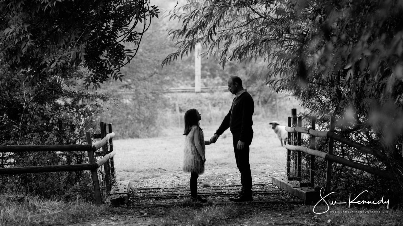 outdoor family photo taken in black and white of a father and daughter facing each other