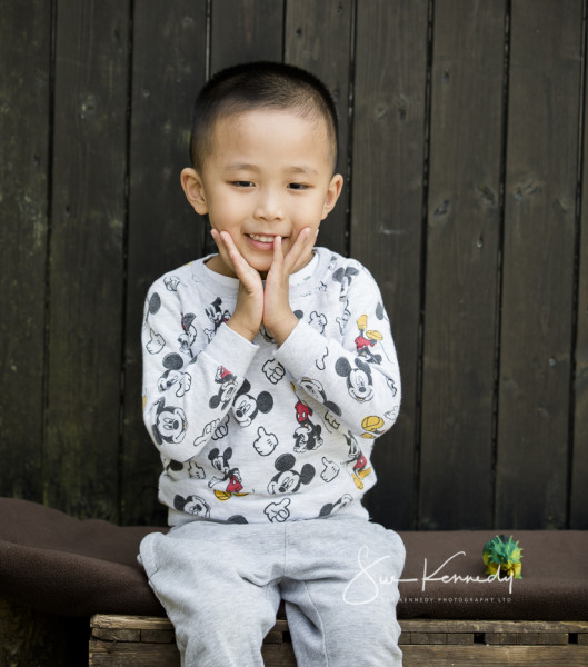 Toddler boy sitting with his hands just below his chin clapping