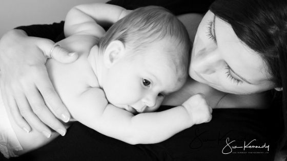 black and white photograph of baby lying on mums chest and being cuddled in black and white shot from overhead