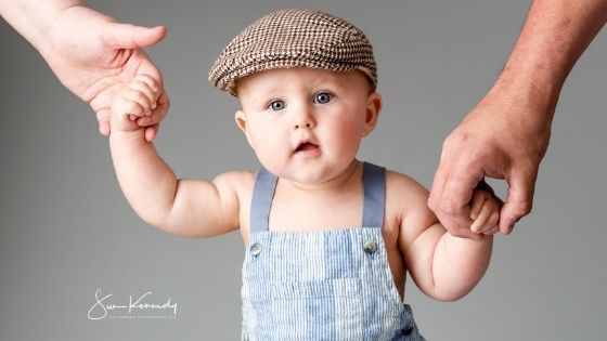 photographs of a toddler standing holding the hand of each parent