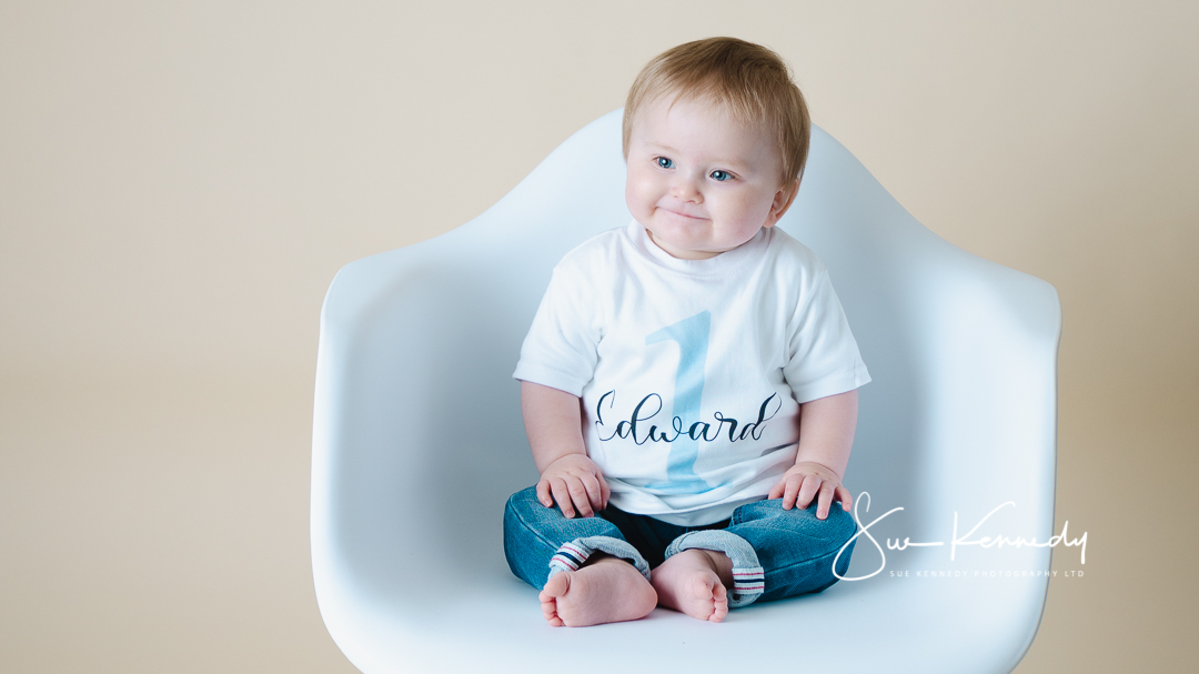 11 month old baby sitting on white chair for quick take portrait session
