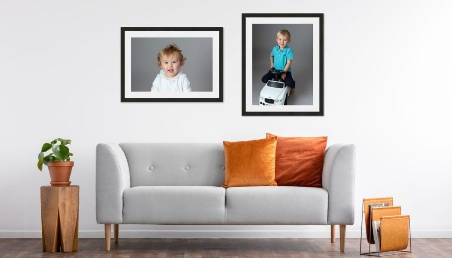 Framed portraits above a sofa with orange cushions