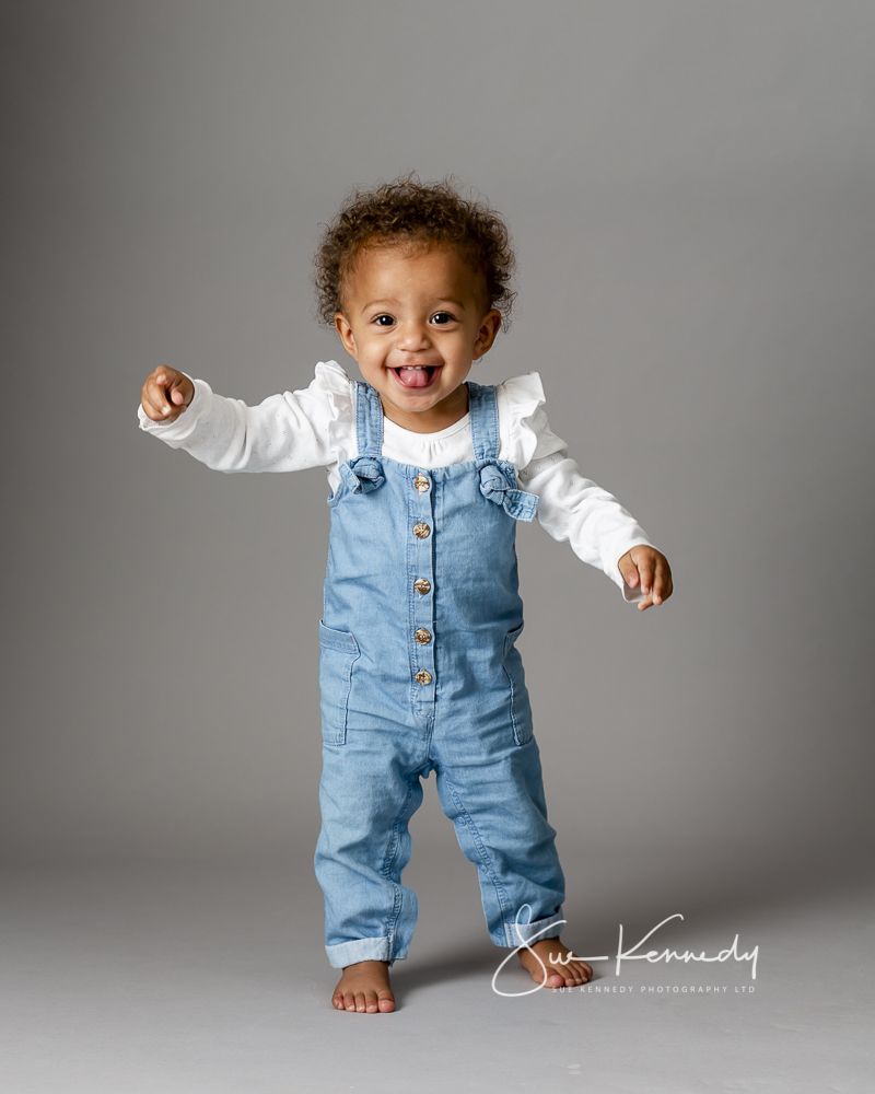 toddler standing and smiling at the photographer