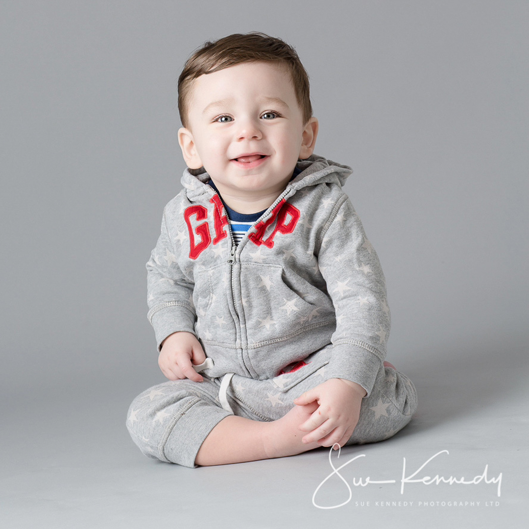 toddler sitting crossed legged smiling at camera