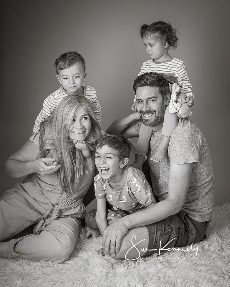 informal black and white photographs of parents and their three young children giggling together.