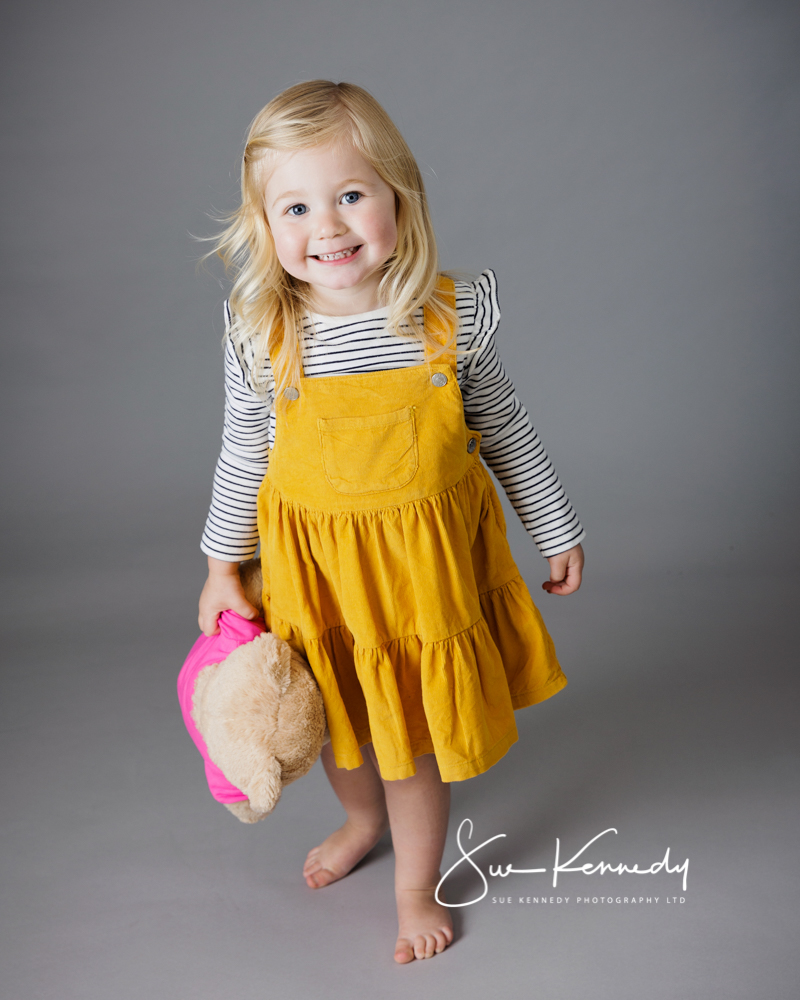 Little girl holding her favourite toy bear and smiling toward camera. 