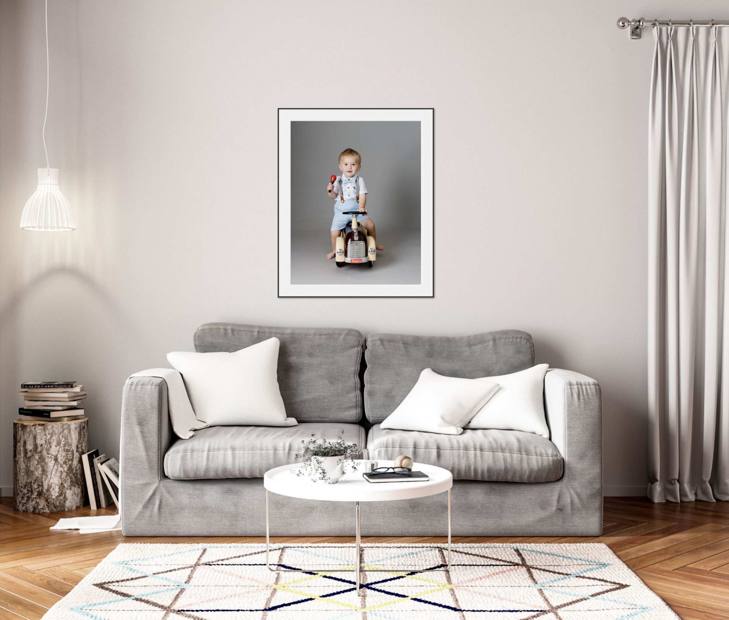 Living room scene with a grey sofa and a framed portrait photograph above the sofa.