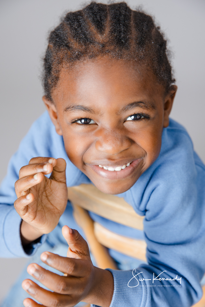 Young child laughing and leaning forward in a brightly lit studio portrait.