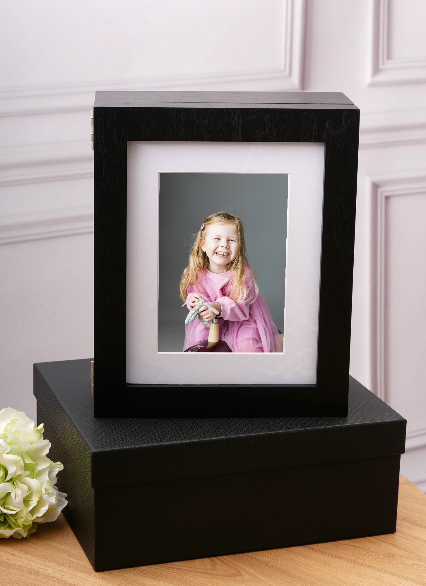 Luxury print folio box with a display window featuring a portrait of a smiling young girl in a pink dress — Sue Kennedy Photography, Harlow, Essex. The folio box holds up to 30 mounted prints, allowing the front portrait to be changed easily.