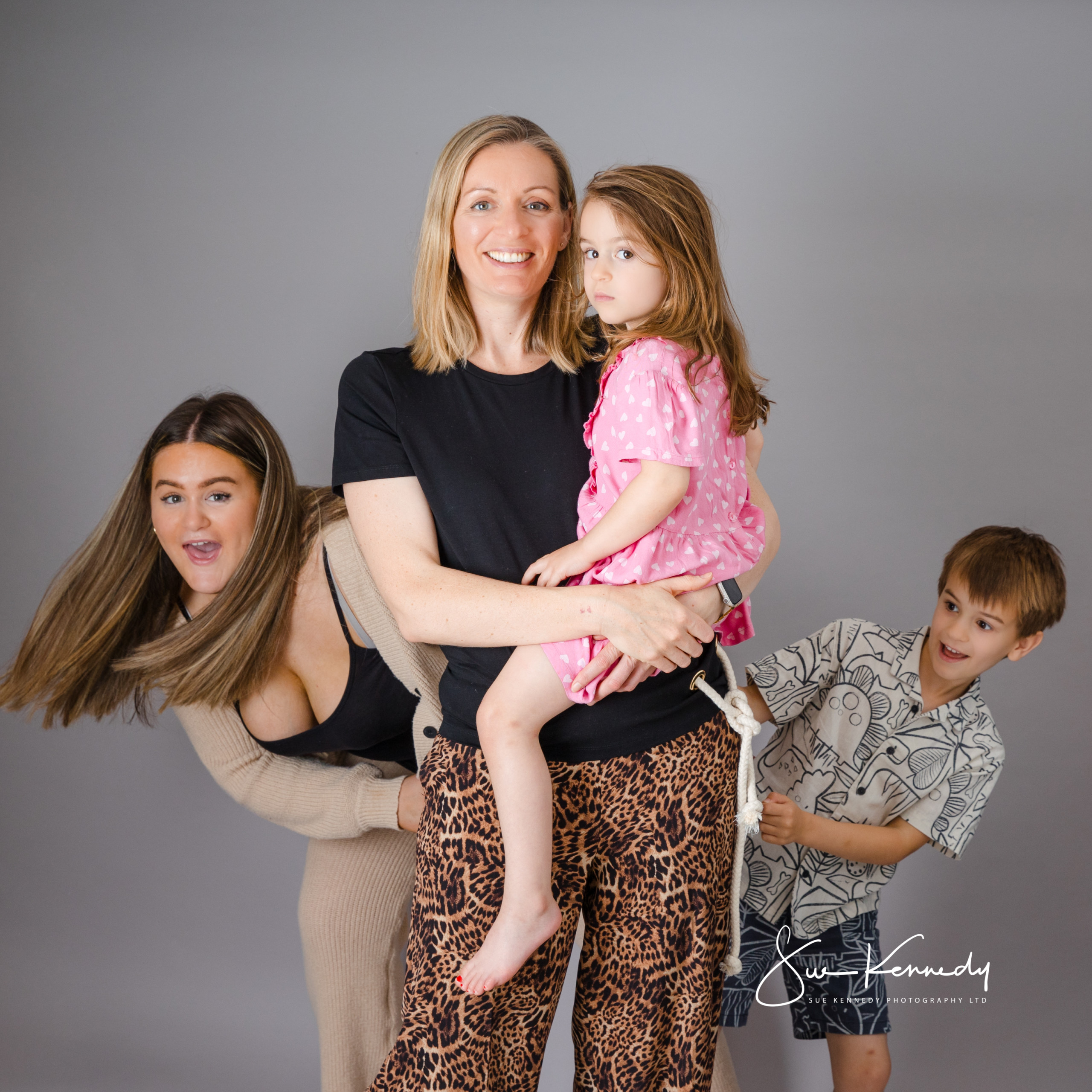 Playful studio portrait of a mother with her children, capturing their lively personalities and natural connection.